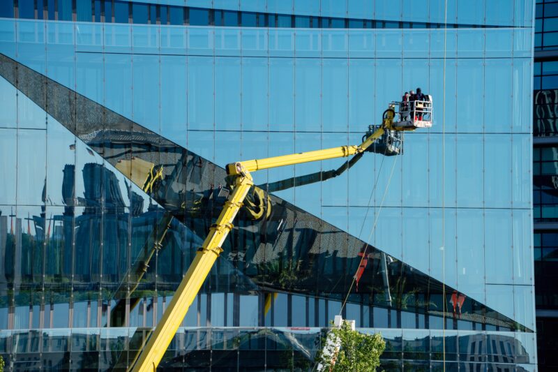 Cleaner,Worker,Using,A,Cherry,Picker,To,Clean,A,Glas